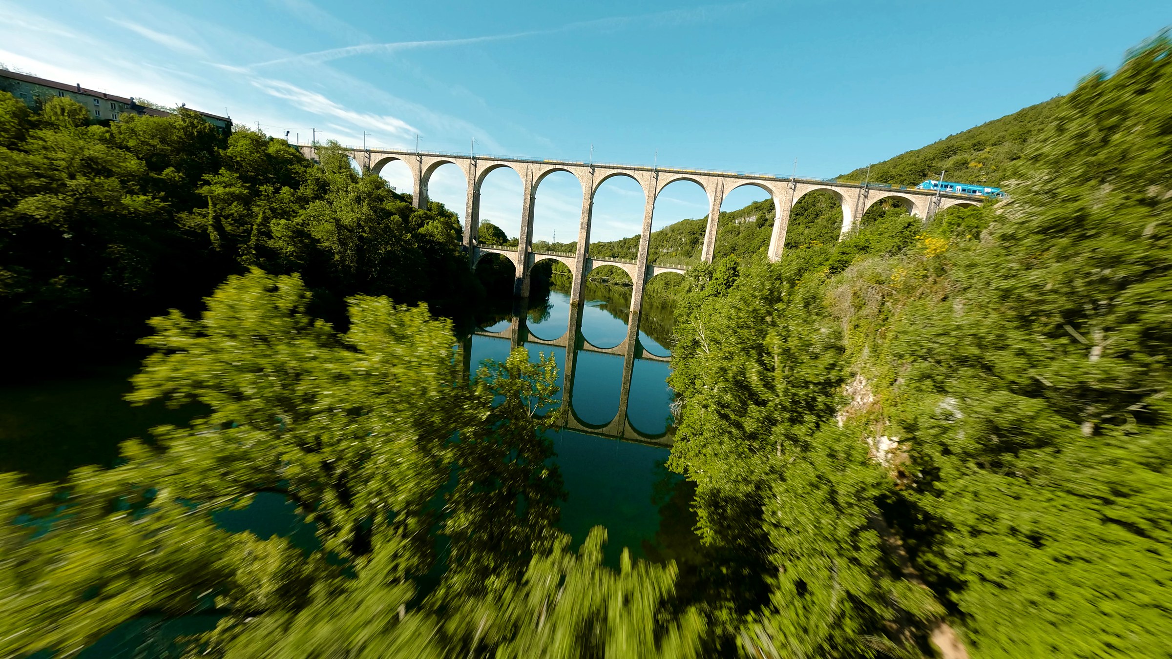 Vol en drone FPV au-dessus des arbres face à un viaduc et sa rivière, filmé par Gabriel Banvillet